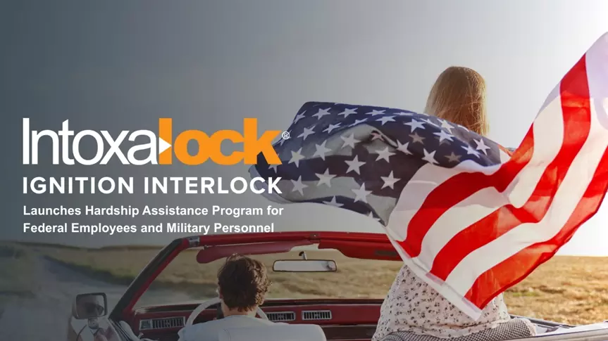 Image of two people in a car with woman holding an American flag
