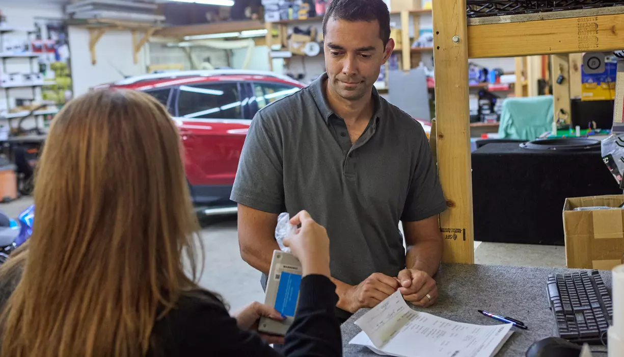 An IID installer demonstrating how to use an ignition interlock device to a customer in a service center