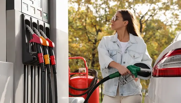 A woman refueling a car at a gas station