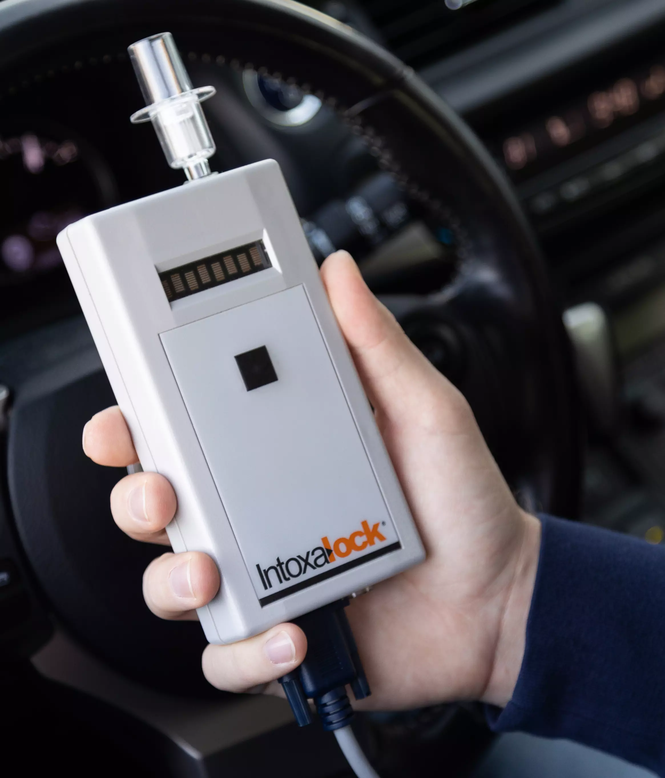 An image of a hand holding an IID in a car.