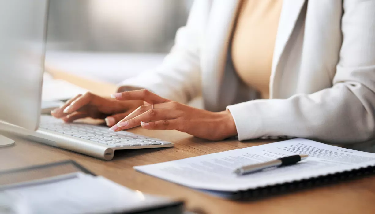 A closeup image of a woman typing on a keyboard.