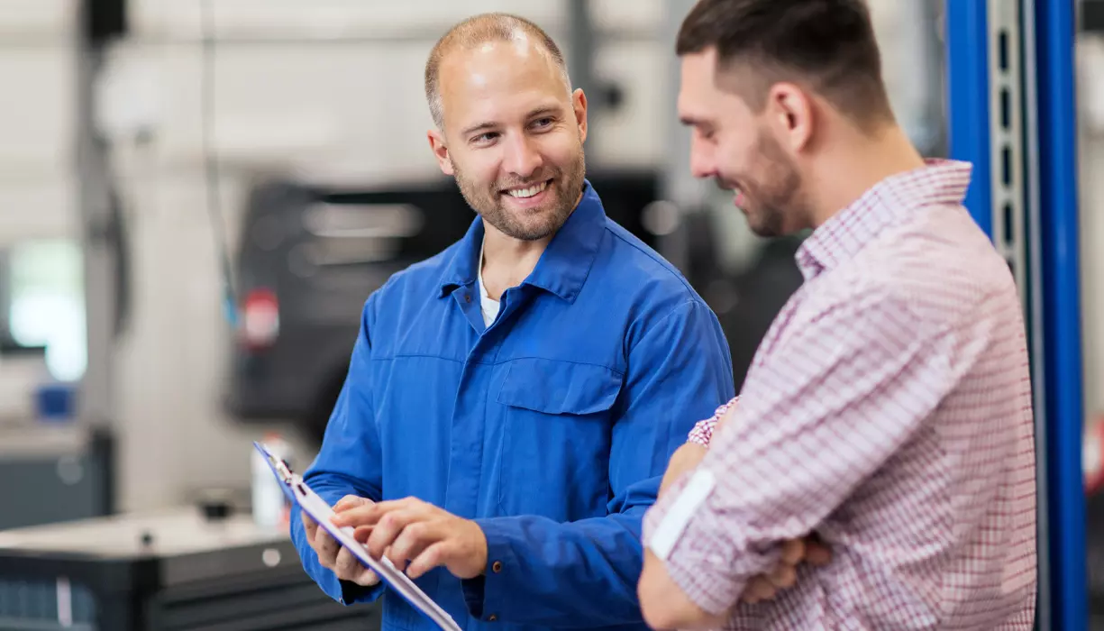 A mechanic pointing at a chart to another person.