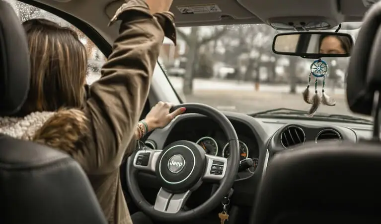 Woman driving a Jeep with her hand reaching out through the sunroof