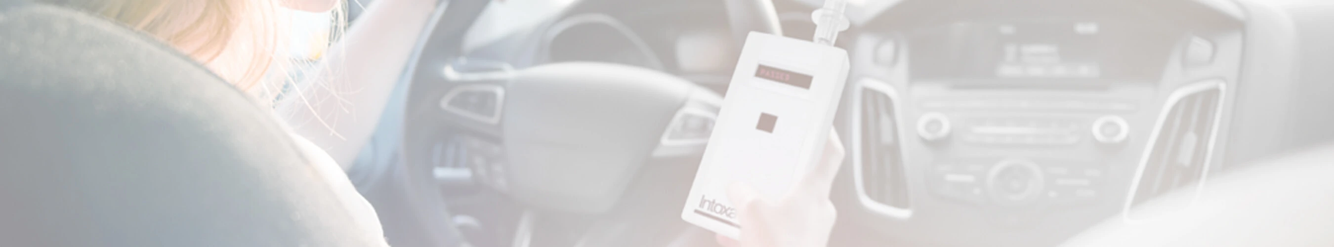 Woman sitting in a car holding an Intoxalock ignition interlock device