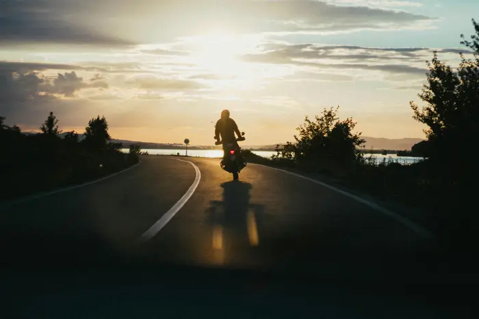 Motorcyclist riding toward the sunset on an open road